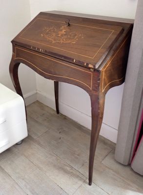 a small desk with a drawer on it in the corner of a room