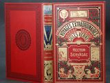 an old book with a red cover sitting on top of a table