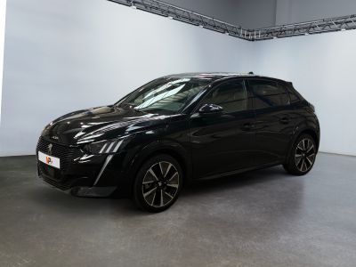 La voiture noire est garée dans une grande pièce aux murs blancs.