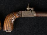 two antique pistols with wooden grips on a black background