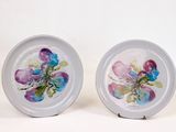 deux assiettes avec des fleurs peintes dessus, posées sur une table