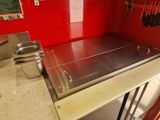 un plan de travail en acier inoxydable dans une cuisine aux murs rouges
