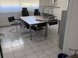 une pièce équipée d'un bureau, de chaises et d'une poubelle