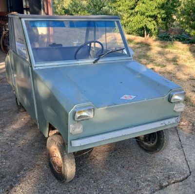 un petit camion vert garé devant un immeuble