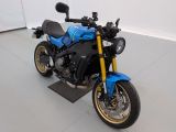 une moto bleue garée dans une pièce aux murs blancs