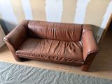 a brown leather couch that is sitting on a wooden floor