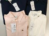 trois chemises pour homme, encore étiquetées, posées sur une étagère