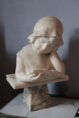 a marble statue of a girl reading a book on a table