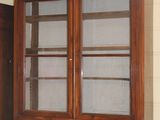 a wooden cabinet with glass doors in the corner of a room