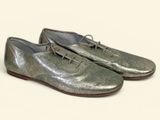 silver leather shoes with laces on them on a white surface