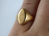 a close up of a person ' s hand with a gold signet ring