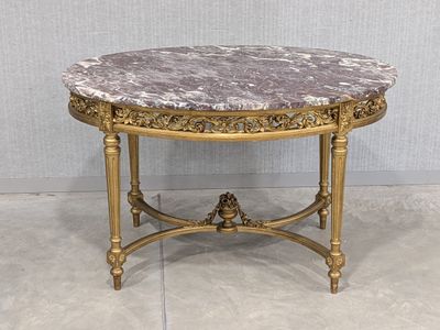 une table au plateau en marbre, avec un piètement doré et un plateau en marbre