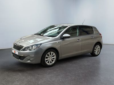 Une voiture argentée est garée dans une pièce aux murs blancs.