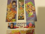 Plusieurs cartes Dragon Ball sont posées sur une table, sur laquelle se détache l'ombre d'une personne.