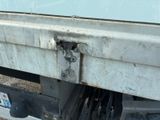 a close up of a white truck with a rusted bumper