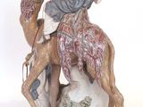 figurine of a man riding a camel on a white background