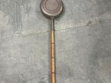 a metal strainer with a wooden handle on the floor