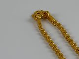 a close up of a gold necklace with a chain on a white surface