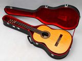 une guitare dans un étui, posée sur une surface blanche