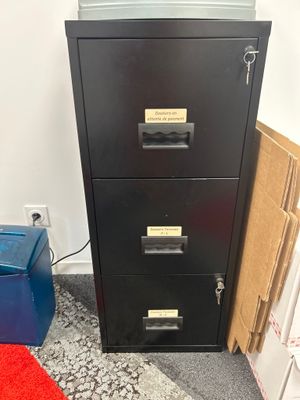un classeur noir à côté d'une poubelle bleue