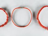 three red necklaces on a white surface