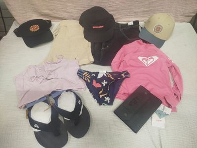 un lit sur lequel sont posés beaucoup de vêtements et de chapeaux