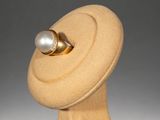 a gold ring with a pearl on top of a mannequin