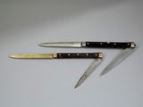 two knives on a table with a knife holder on top of it