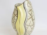 a white vase with a yellow and black stripe on it