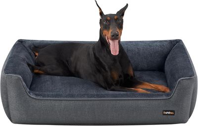 Le chien est allongé sur son panier, la langue pendante.