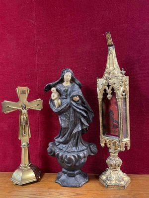 a statue of a woman holding a baby next to a cross and a mirror