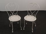 pair of white wrought chairs on a black carpeted floor