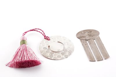 a key, a keychain, and a coin on a white surface
