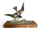 sculpture représentant un oiseau sur une vague, posée sur un socle en bois