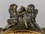 a gold clock with angels on it and a key in the middle
