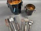 five silver spoons and a bucket of silverware on a table