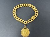 un bracelet en chaîne d'or orné d'une breloque en forme de pièce de monnaie