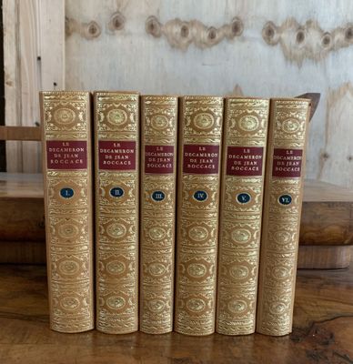 quatre livres posés sur une table, avec une étagère en bois en arrière-plan
