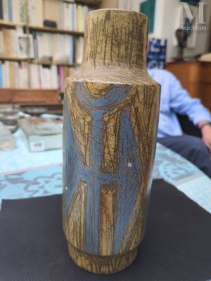 un vase posé sur une table, avec un homme en arrière-plan