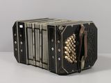 an old black accordion sitting on top of a white table