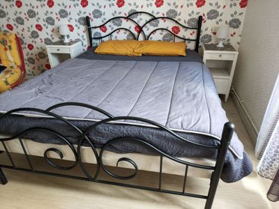 a bed with a metal frame in a room with floral wallpaper