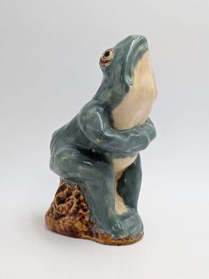 ceramic figurine of a frog sitting on a tree stump