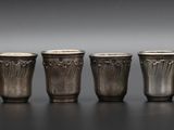 six verres à shot en argent alignés sur une table