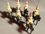 several figurines of soldiers riding on horses on a gray surface