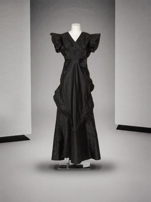 une photo d'une robe noire posée sur un présentoir à mannequin dans une pièce