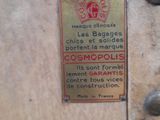 a sign on the side of a suitcase that says cosmopolis
