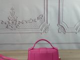 pink handbag on a wooden table in front of a white wall