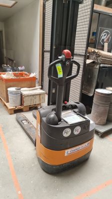 a fork lift truck in a warehouse with other items in the background