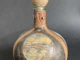 a bottle with a painting on it sitting on a table