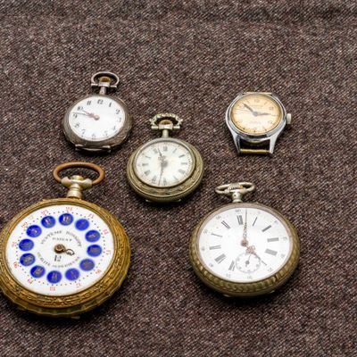 plusieurs montres de poche de différents types posées sur une surface marron